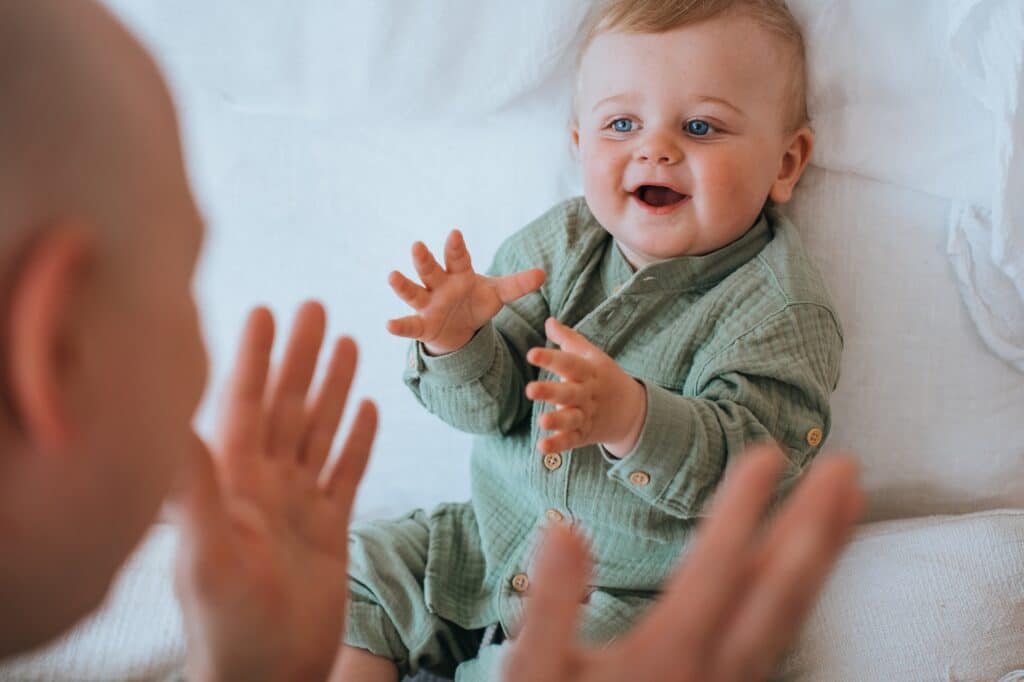 Cropped image of caucasian father playing with little boy laying on bed. Cute cheerful toddler