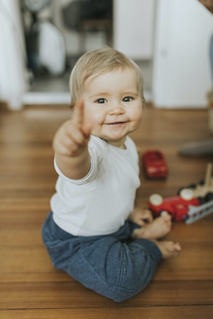 Smiling baby girl pointing finger at home
